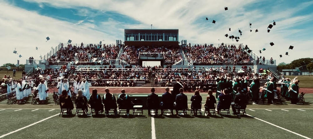 OHS Class of 2026 Graduation. Whole graduation view of the moment graduates threw their caps in the air with the audience in the background.