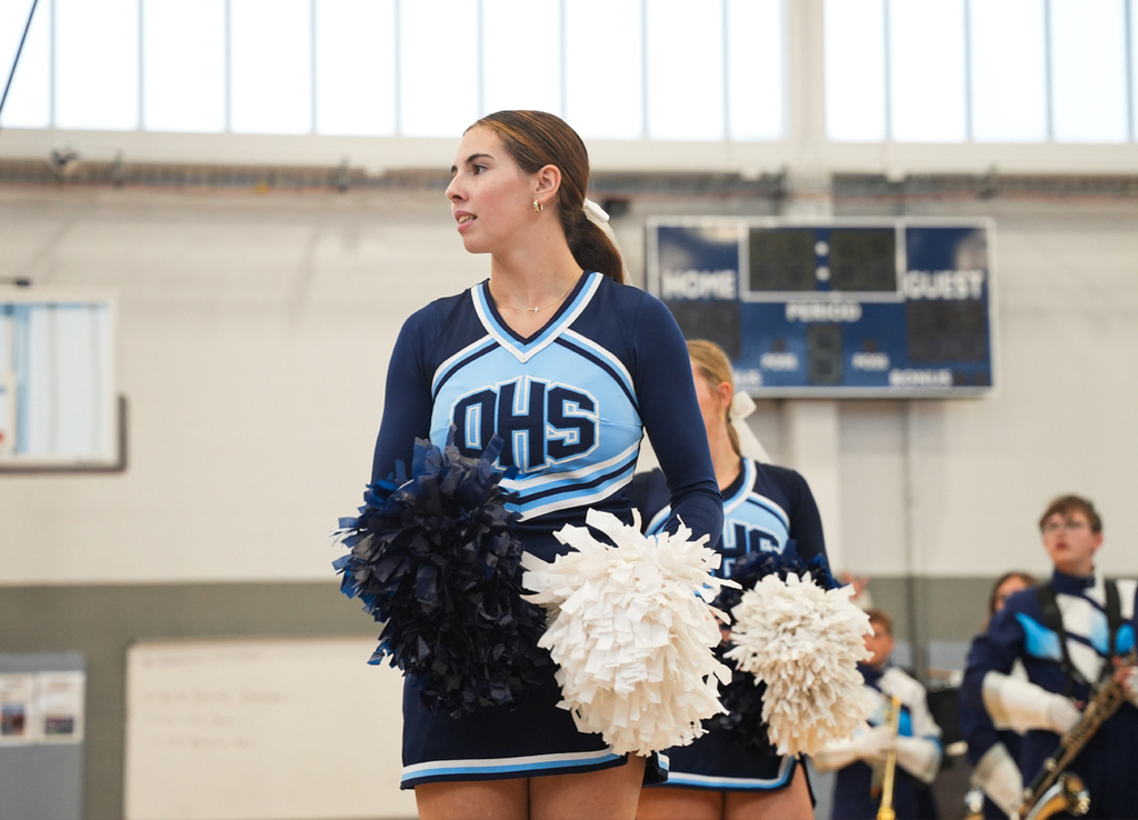 Cheerleader with blue and white pom poms leading a cheer