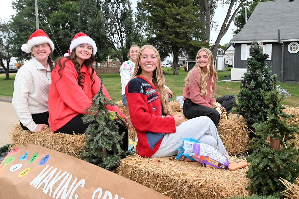Female students sit on hay bales as part of a parade