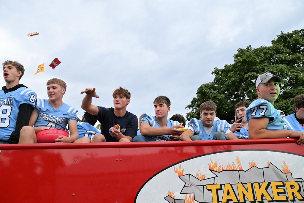 Boys in blue jerseys throwing candy in a parade