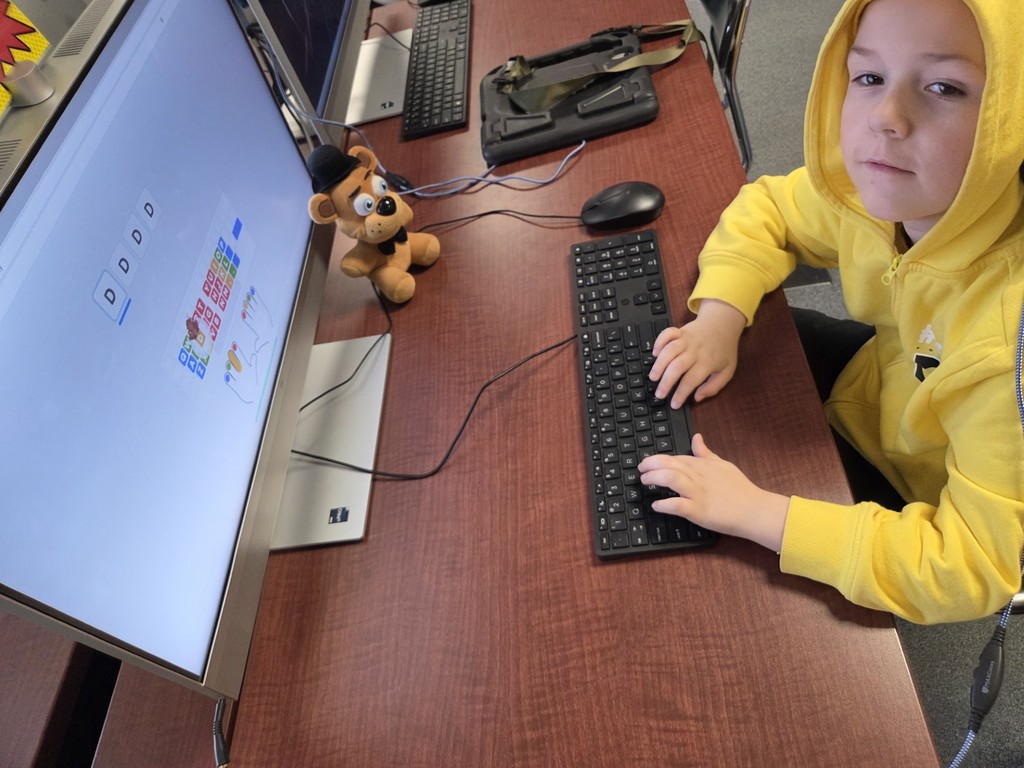 A 1st grade student is learning where the letter D is on the keyboard.