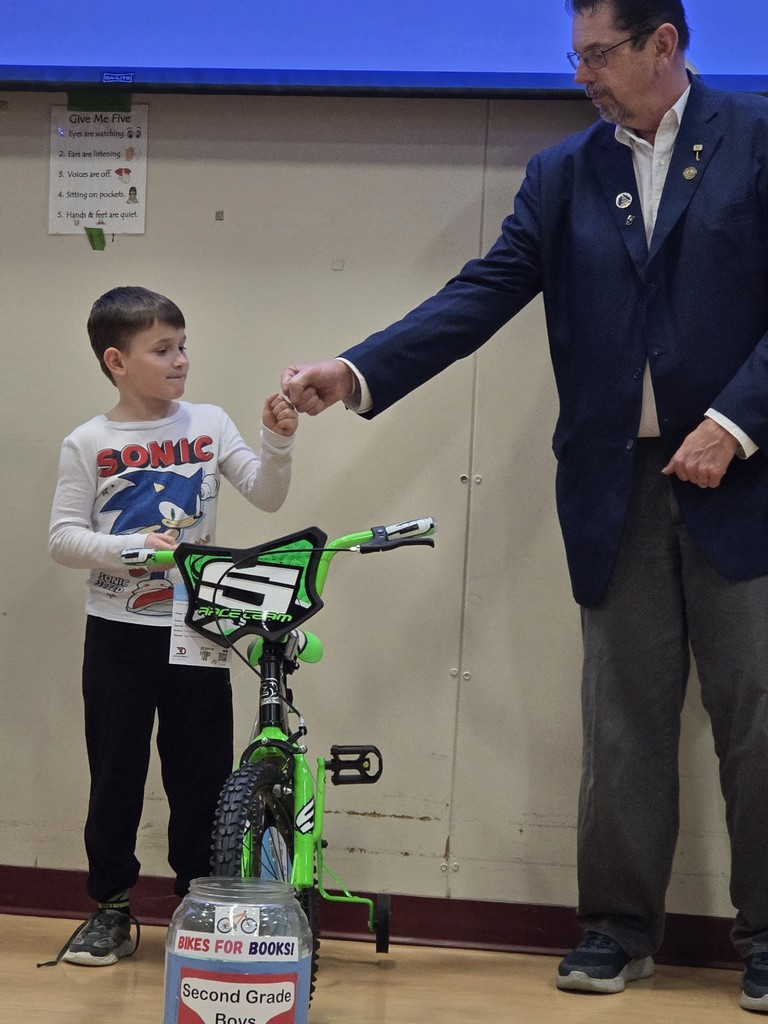 A 2nd grade bike winner shares a fist bump with a Mason.