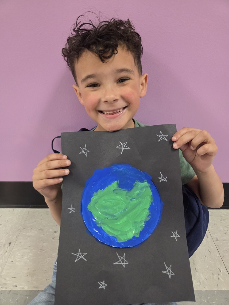 A kindergartener at North Elementary shows off his Earth art and his great big smile!