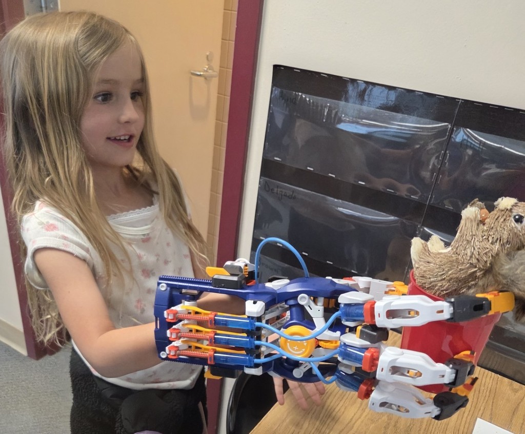 A Kindergarten student looks excited as she uses the Mega Cyborg Hand for her first time.