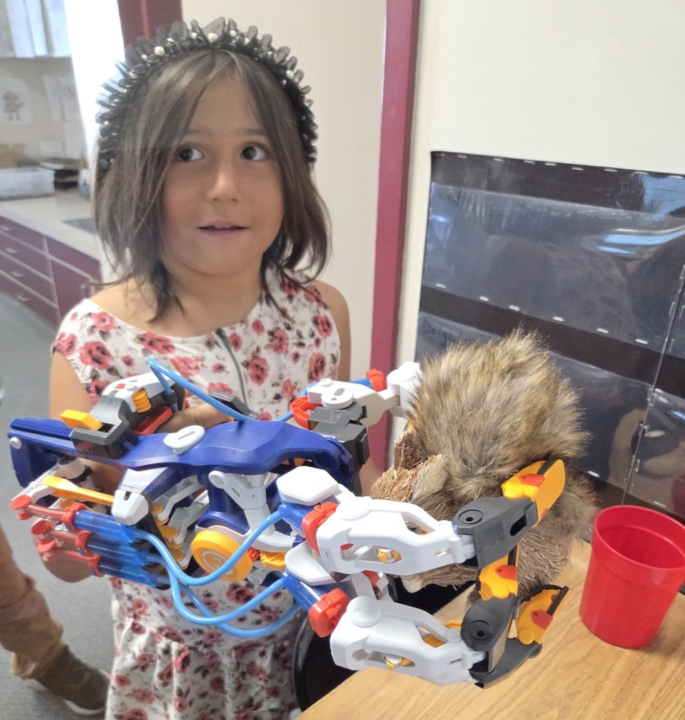A 2nd grade student uses the Mega Cyborg Hand to pick up a toy squirrel.
