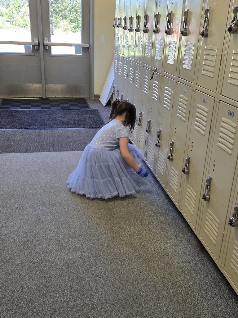 student picking up trash in the hallway
