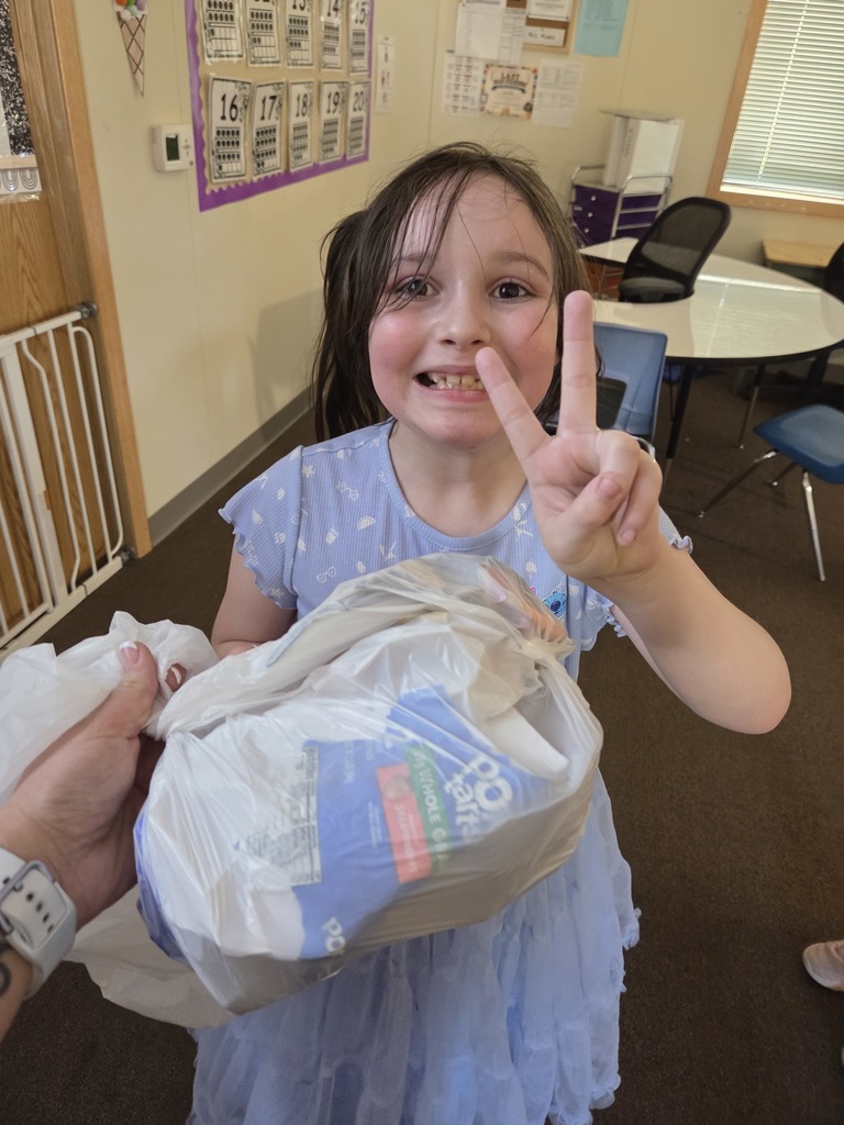 student giving the peace sign while holding a trash bag