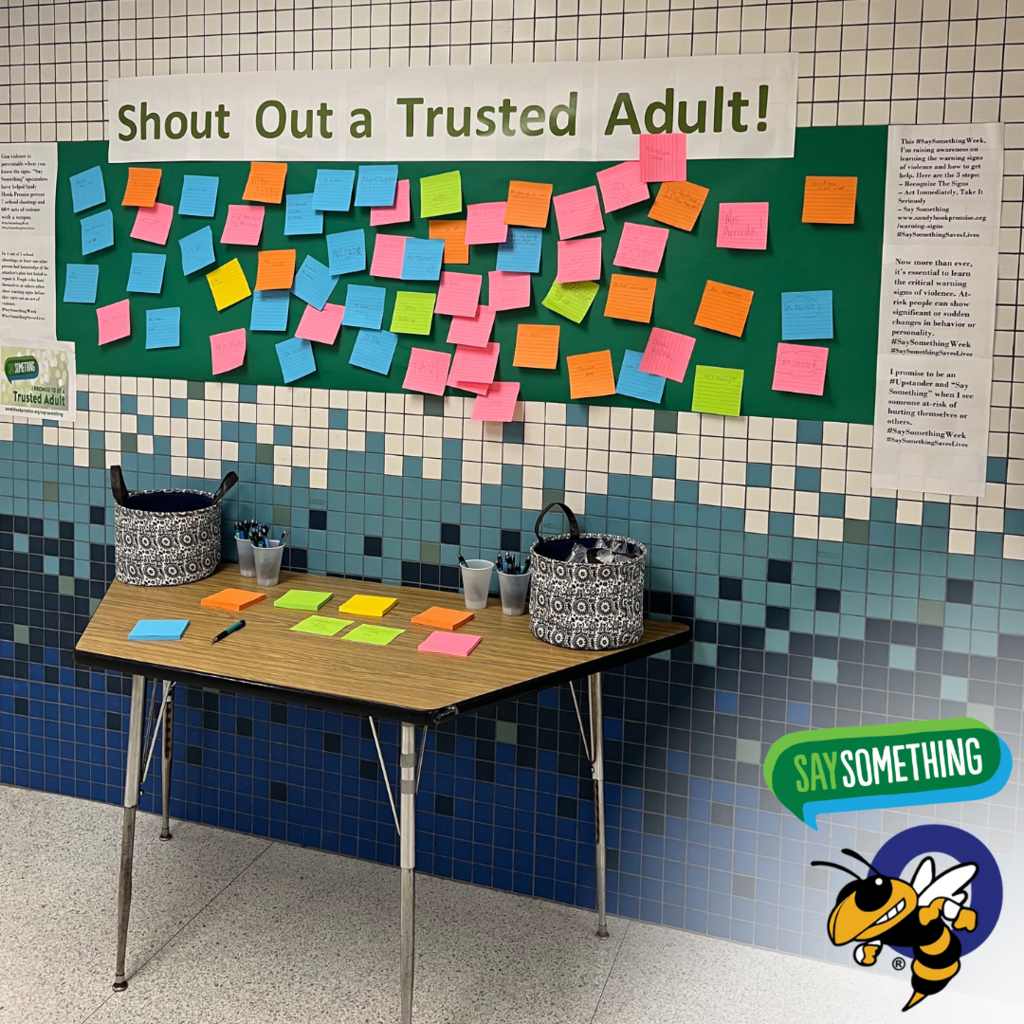 wall with post-it notes and a sign that says "Shout Out a Trusted Adult!"