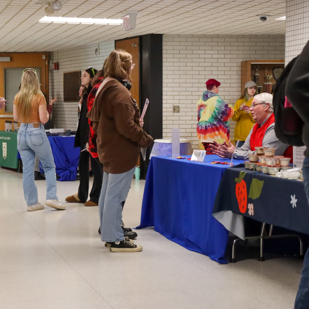 group of students standing in line at tables in a hallway.