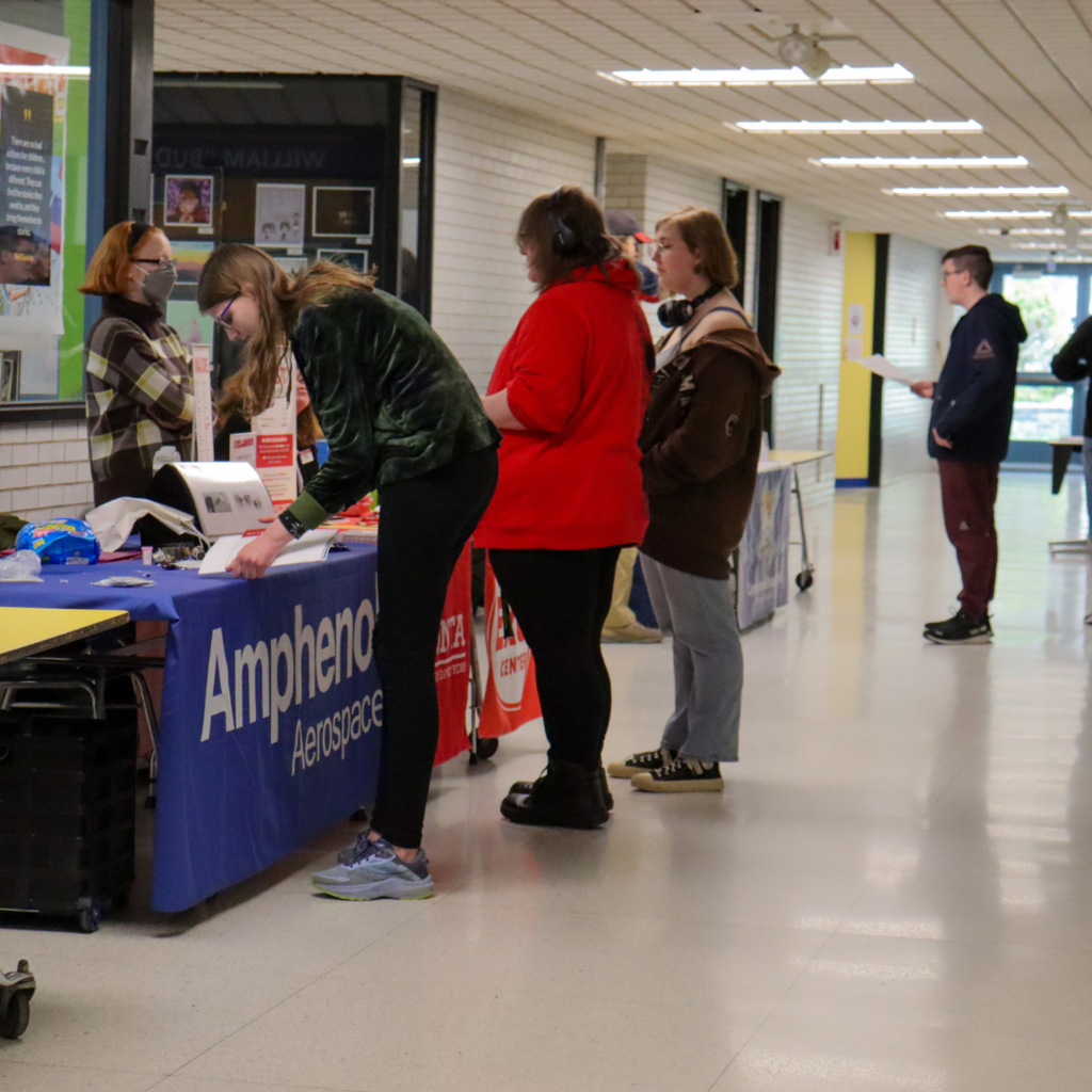 group of students standing in line at tables in a hallway.