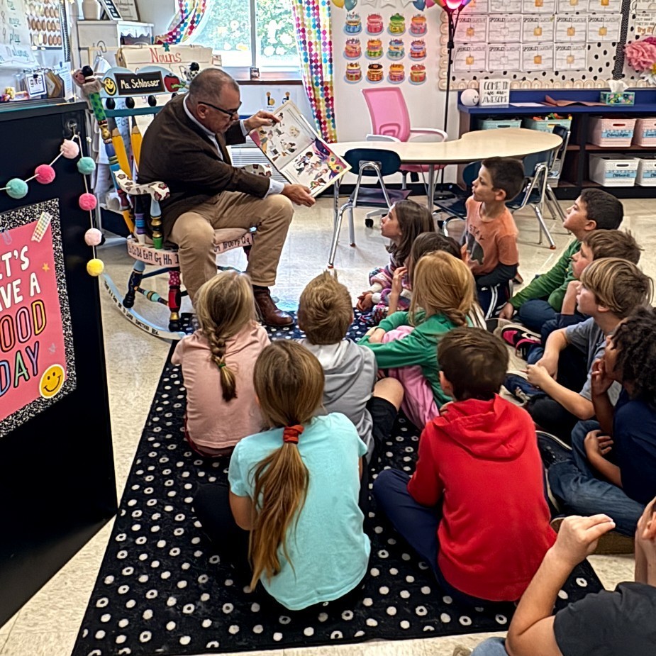 Senator Burger reading a book to the second grade class.