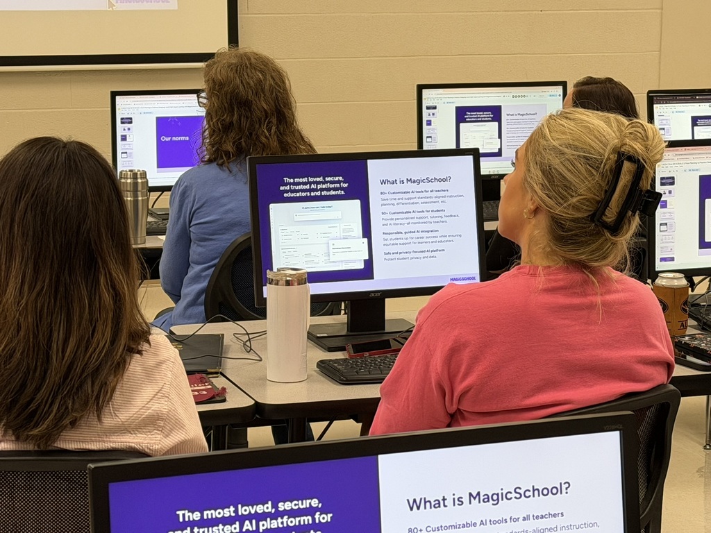 Educators seated in a computer lab view a presentation introducing MagicSchool and its AI tools for teachers.