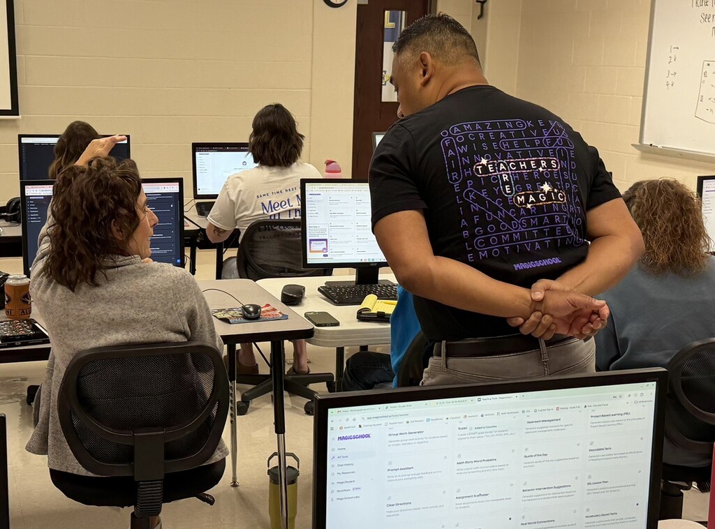 Presenter assists educators seated at computers as they explore MagicSchool tools during a professional learning session.