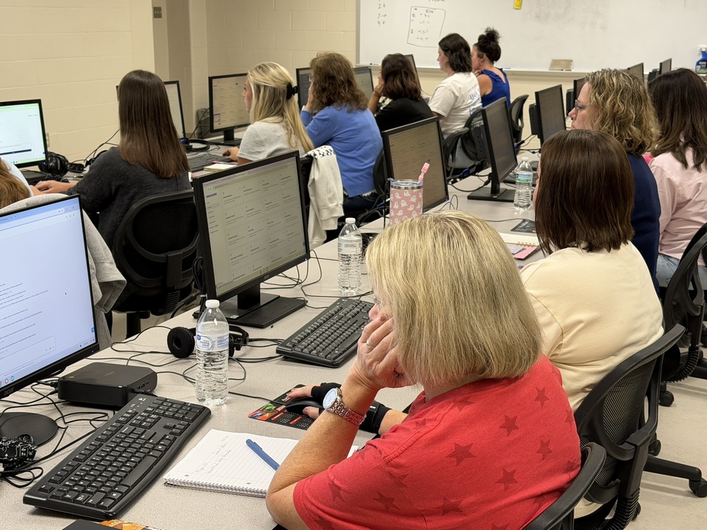 Educators work at rows of desktop computers during a hands-on professional learning session focused on digital tools.