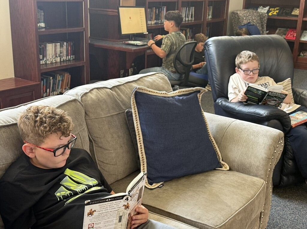 Students sitting on couches in a library reading books