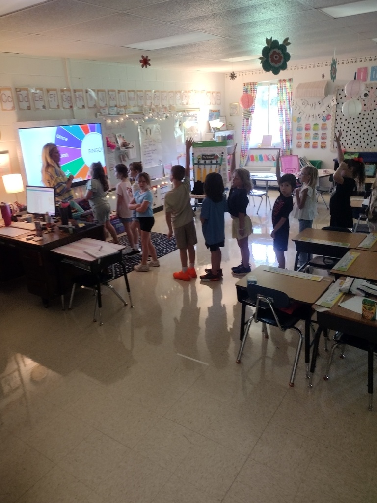 Children in a classroom with their hands raised.