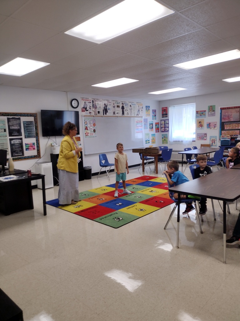Teacher speaking to children in a classroom seated at a table