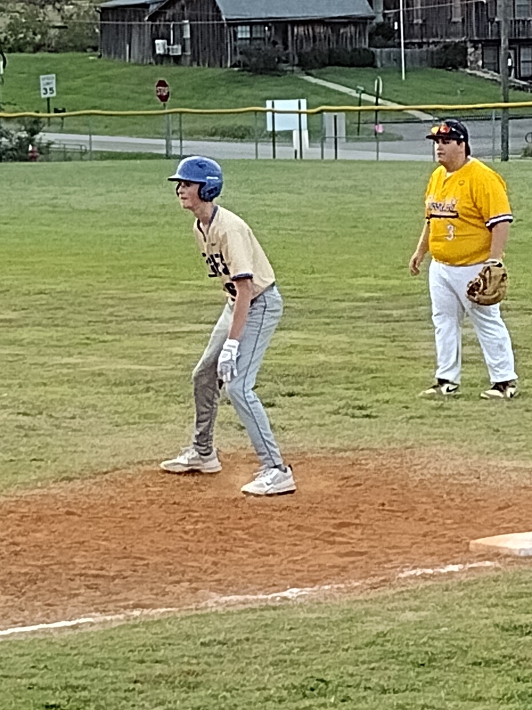 Image 1: Baseball player in a blue helmet takes a lead off first base as an opposing fielder stands nearby.