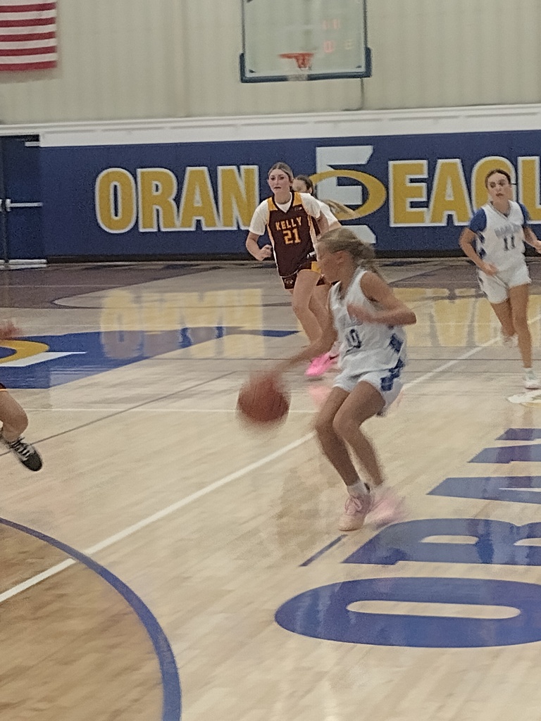 A player in a white uniform dribbles down the basketball court as maroon-clad defenders pursue her.