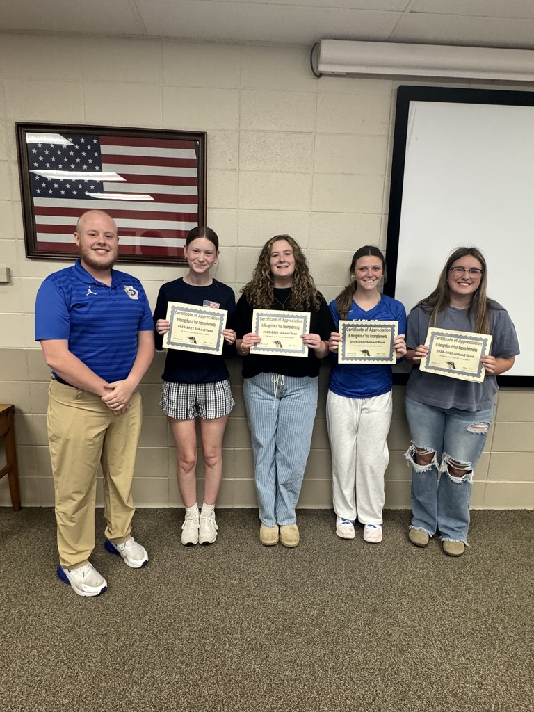 Four students standing next to an adult holding certificates.