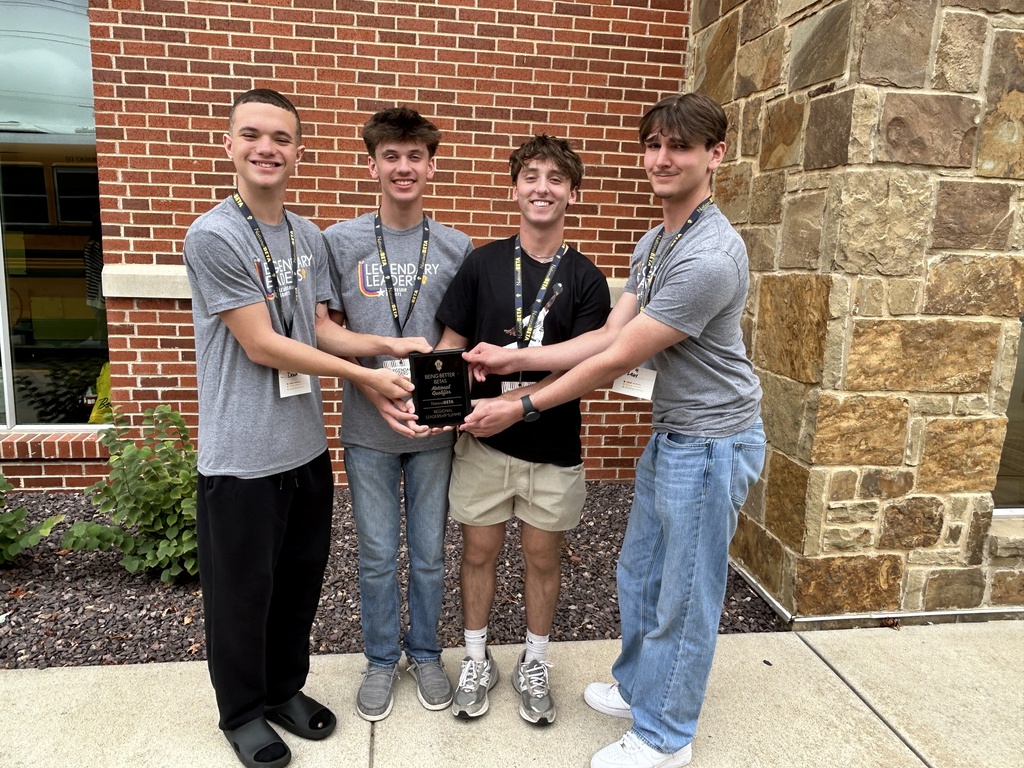 Four students smile outside while jointly holding a “Being Better Betas” regional leadership award plaque.