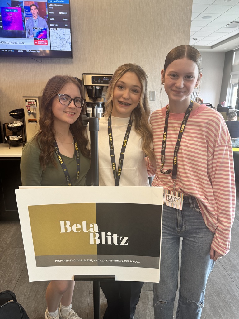 Three students wearing National Beta lanyards pose behind a “Beta Blitz” presentation board from Oran High School.
