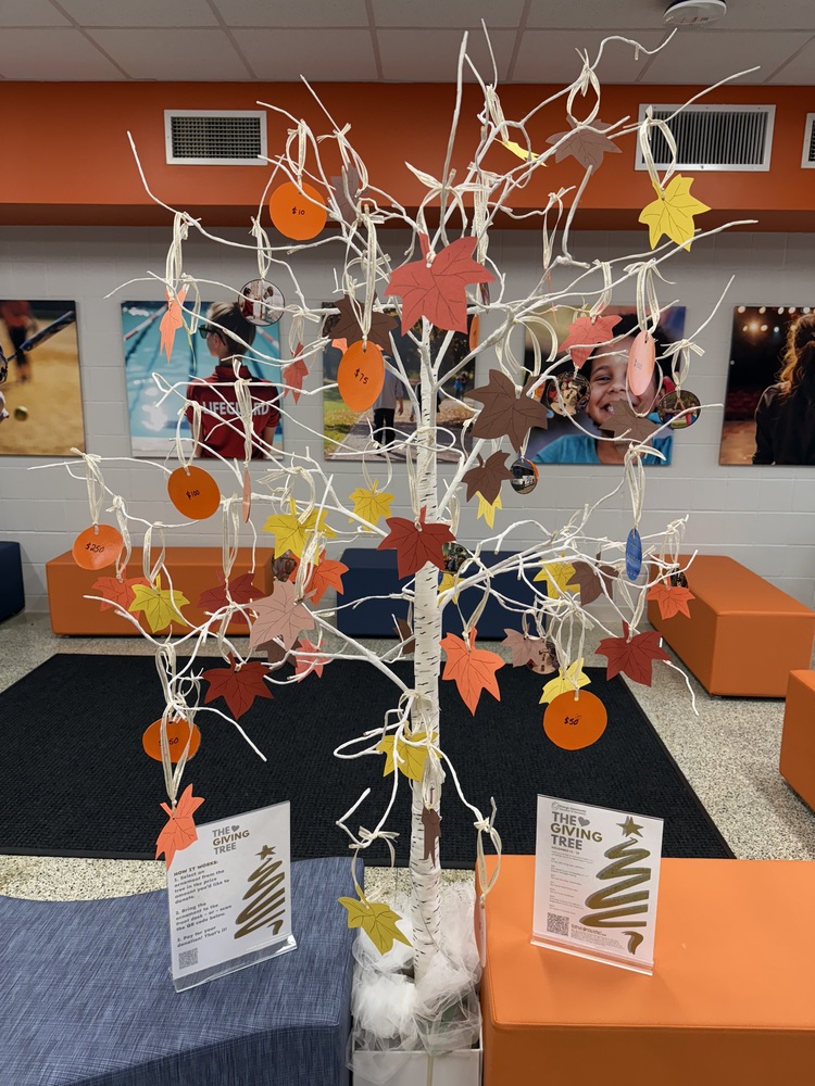 A white tree in the lobby of PPLC with ornaments hanging off of it with leaves and dollar amounts on the ornaments