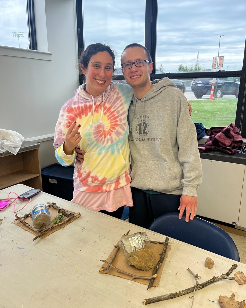 Two participants standing and smiling, with their homemade fairy gardens on the table in front of them