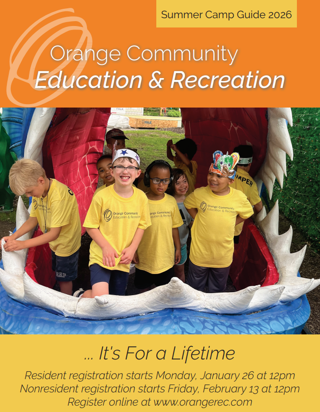 A group of students in yellow tshirts, wearing paper crowns and smiling at the camera