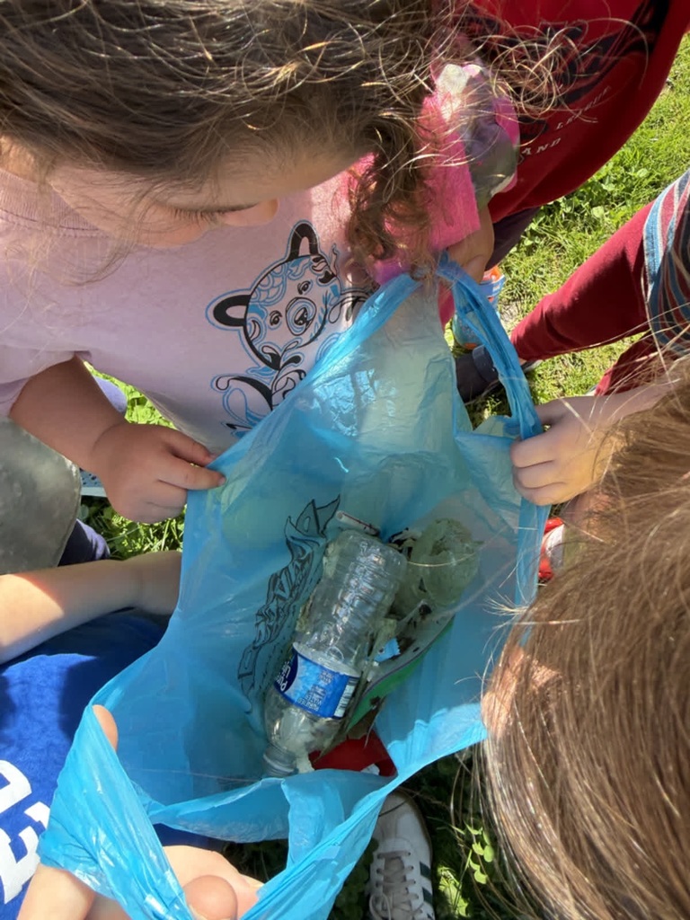 A group of preschoolers huddled around a plastic bag filled with recycling