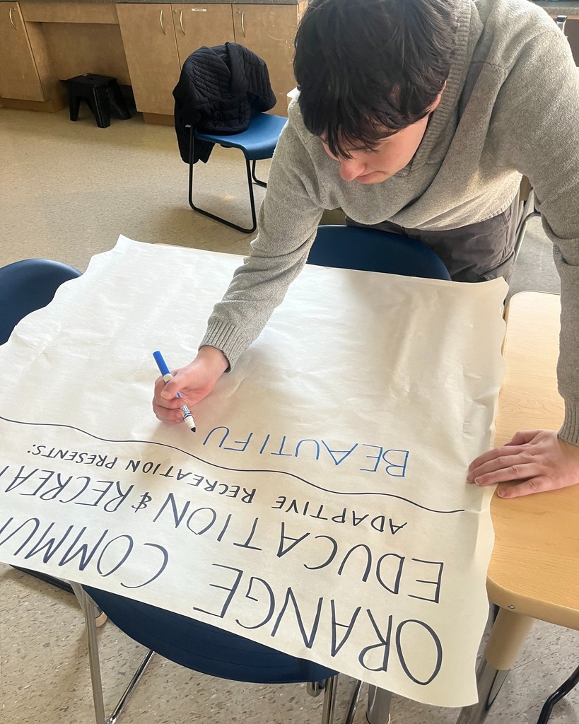 A participant makes a banner with paper and marker for an upcoming Farmers Market