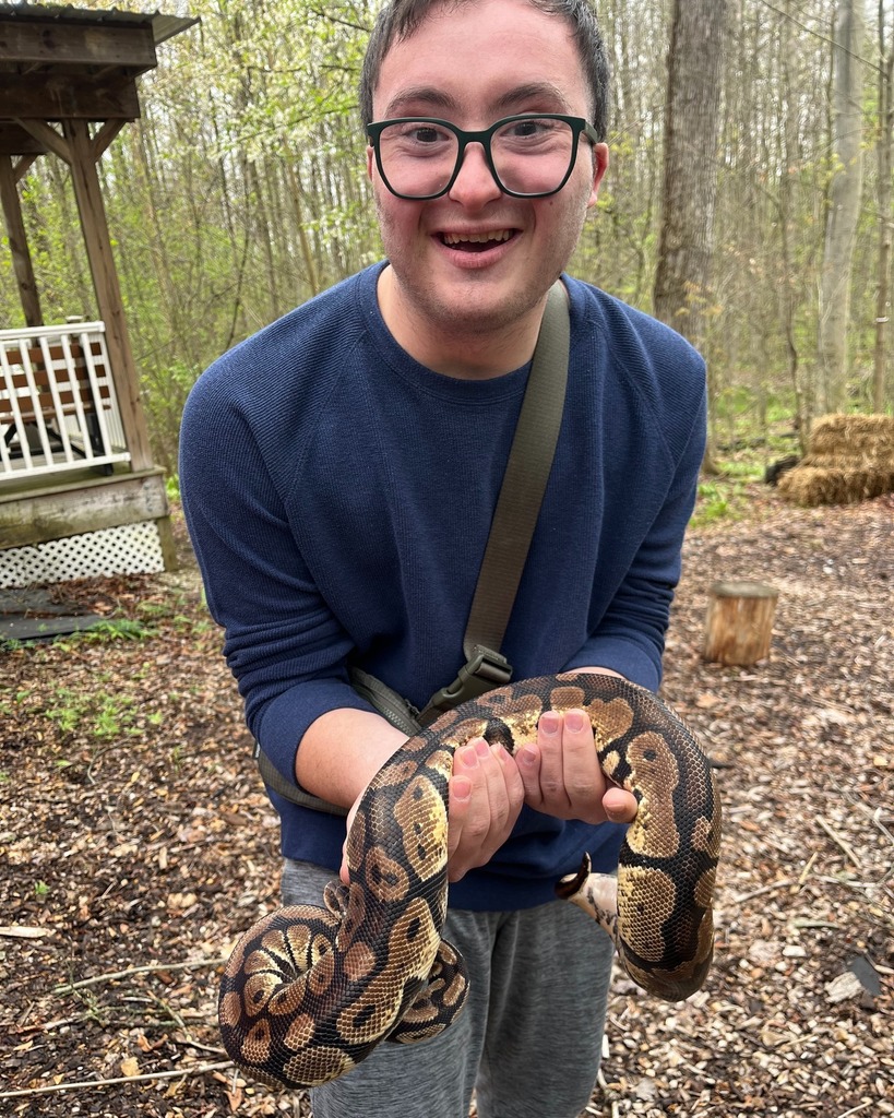 A participants holding a snake and smiling at the camera