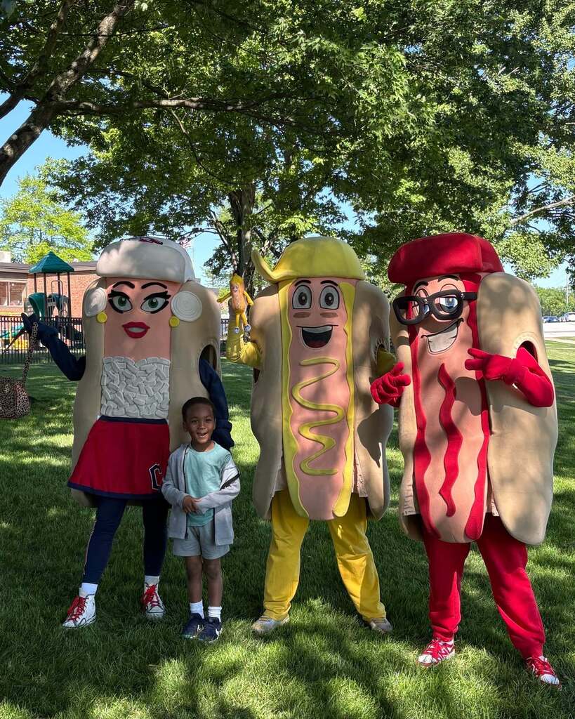 A boy stands in front of the Cleveland Guardians Hot Dog mascots
