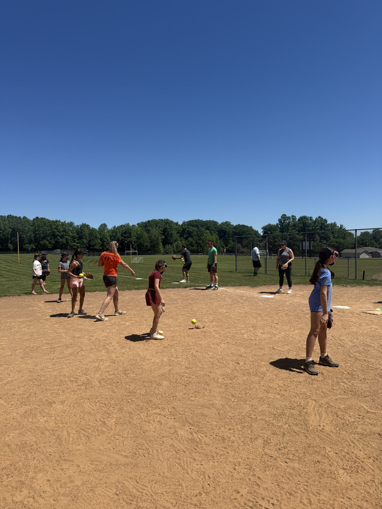 A group of girls outside playing softball on a softball diamond