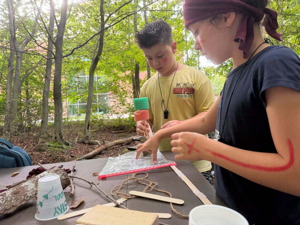 Two students work outside to complete a challenging task
