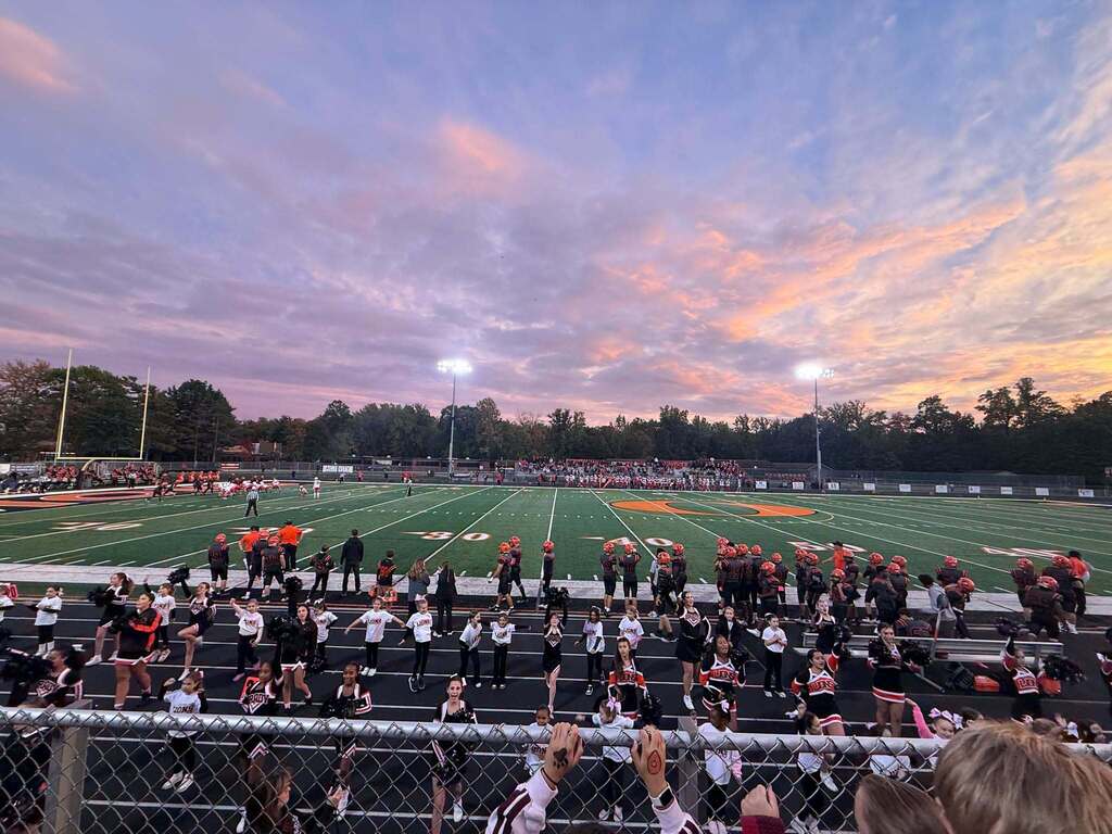Picture of the Orange High School Varsity football game with football players and cheerleaders