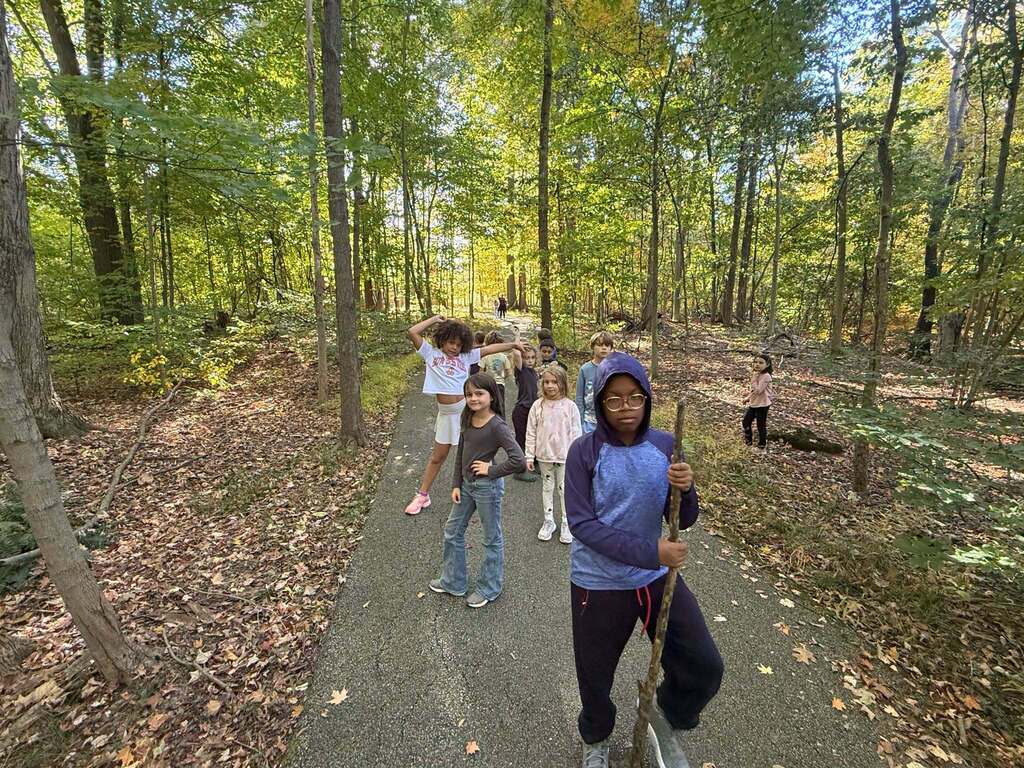 A group of students take a walk on a paved path in the woods