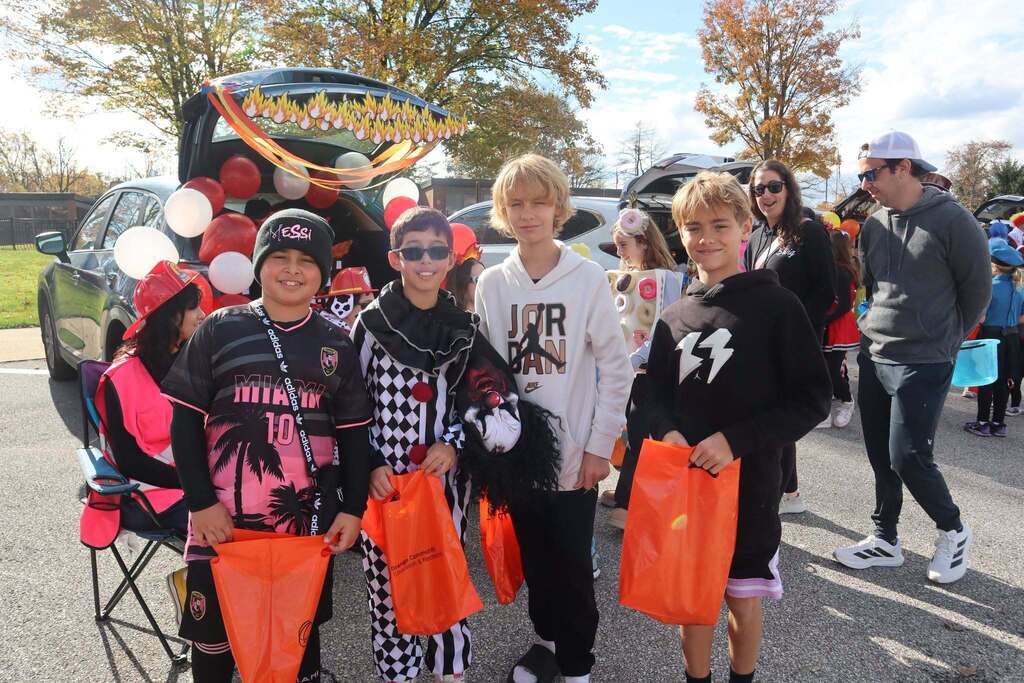 A group of boys in costumes, holding candy bags, smiling at the camera