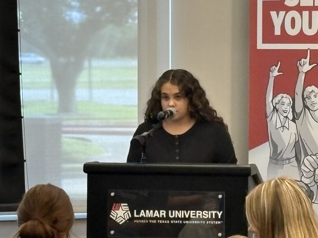 Student reading her piece at a pdium