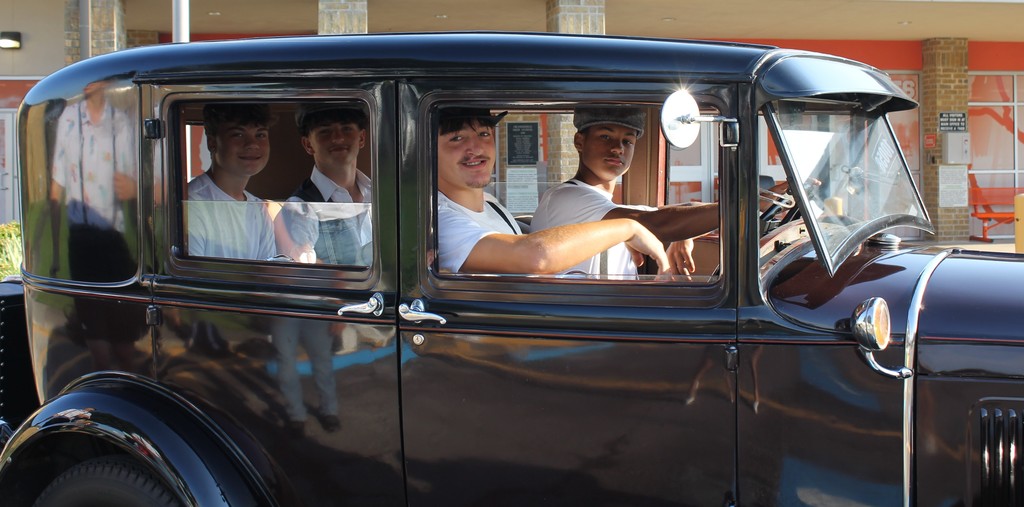 group of four young men in old car