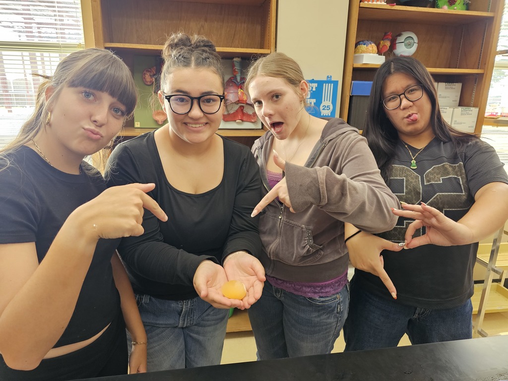 four female students holding a gold egg