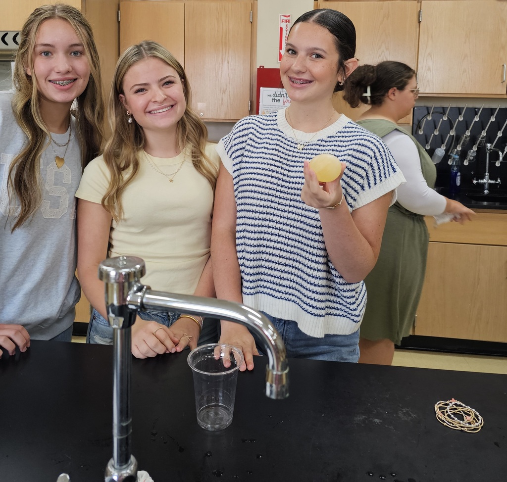 three female students holding a yellow egg