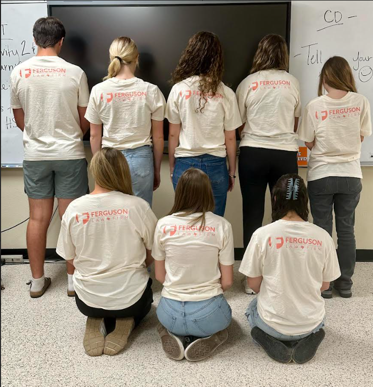 eight students showing back of shirts with Ferguson logo