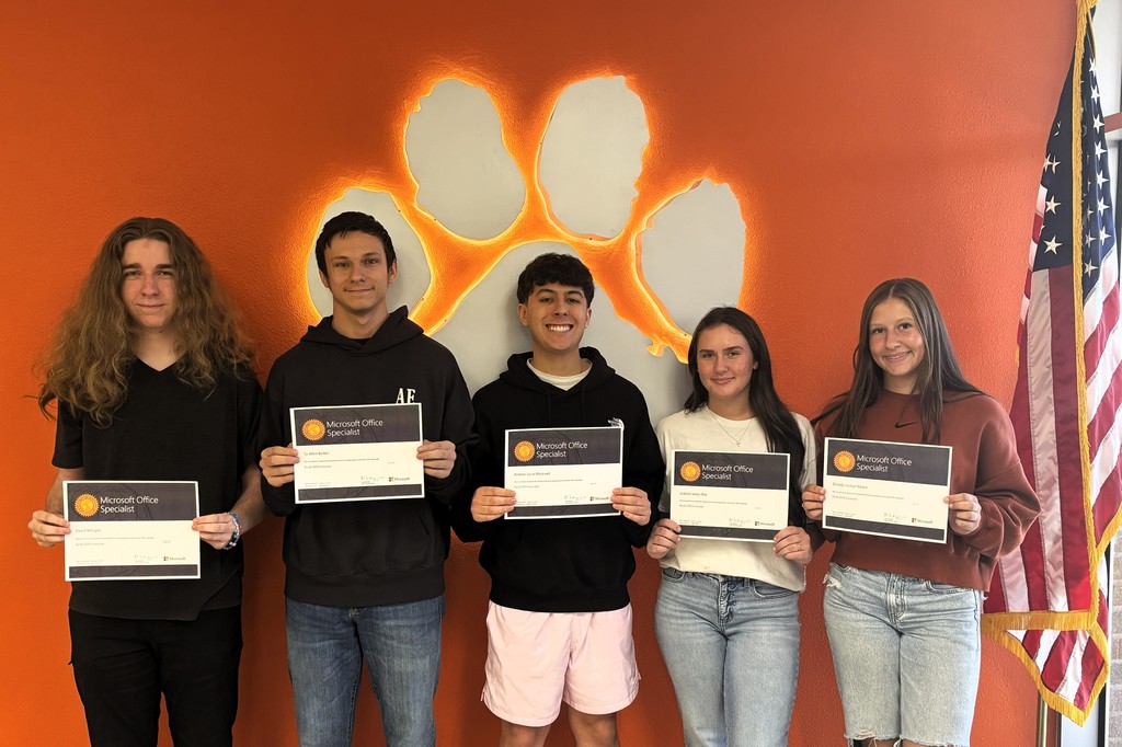 five students holding certificates in front of a paw print