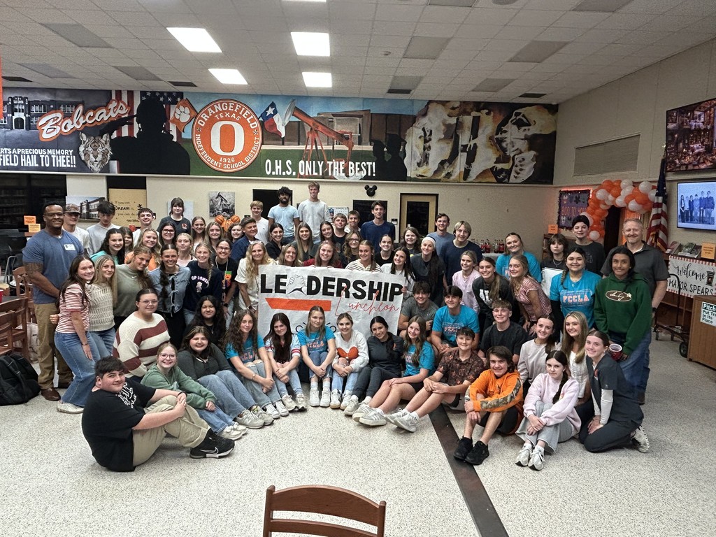 students around a leadership sign in the library