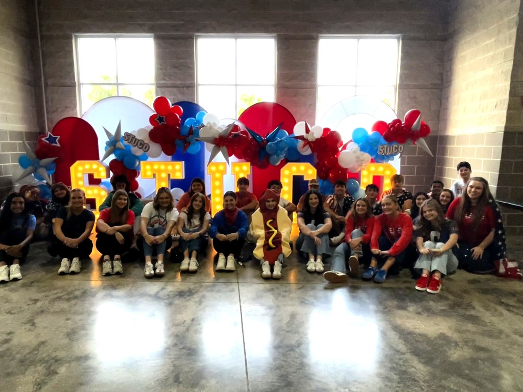students in front of light up STUCO and red, white, and blue balloons
