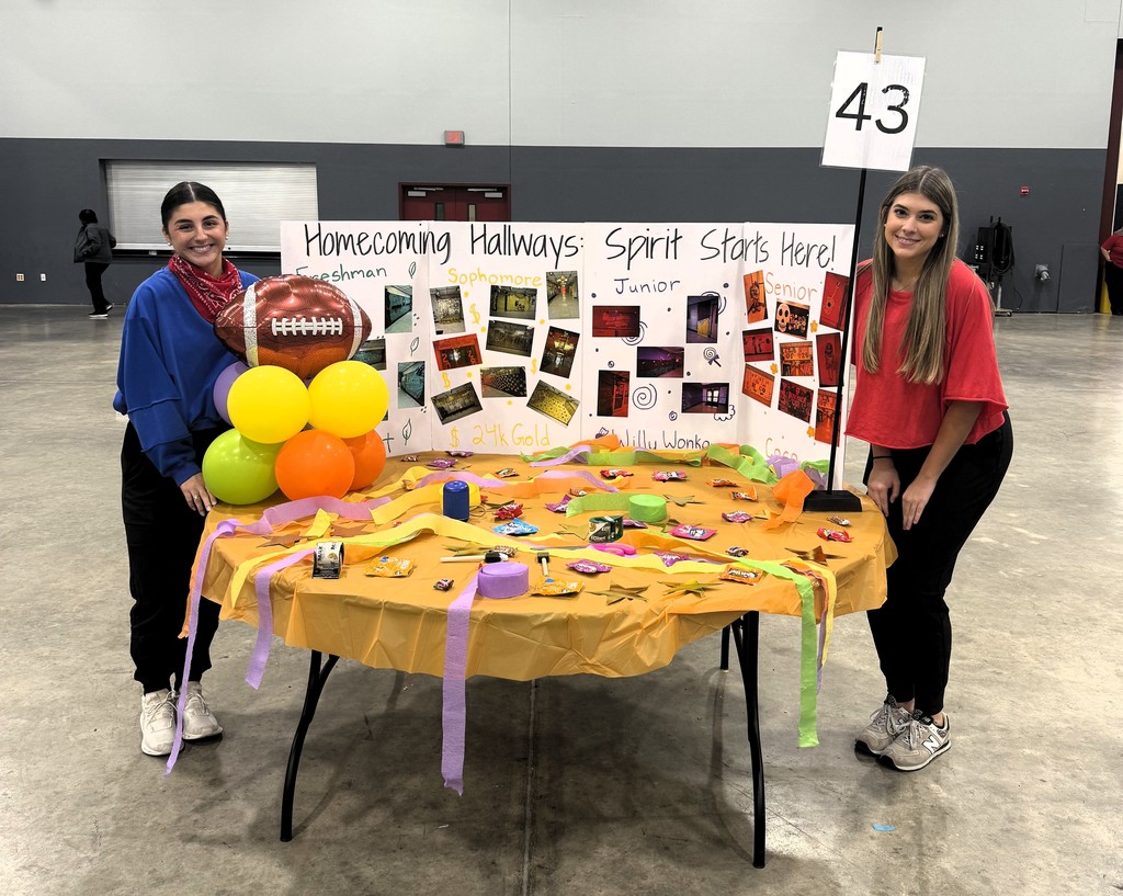 two students with table and poster of pictures