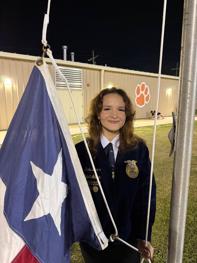 student in FFA jacket raising the Texas  flag