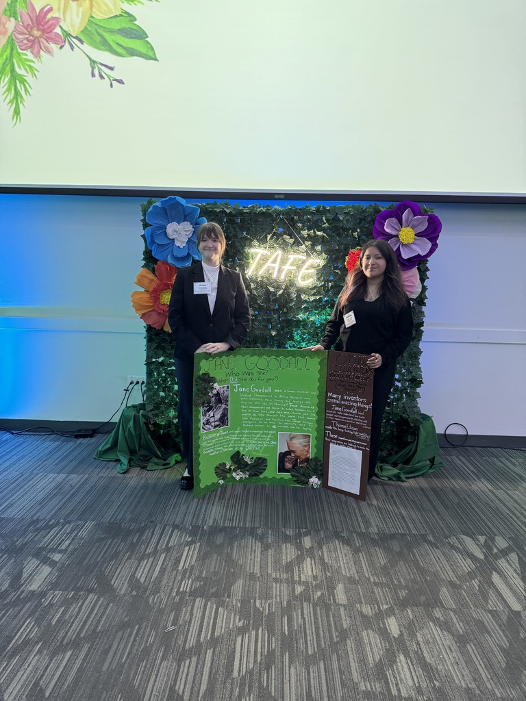 two students with green bulletin board