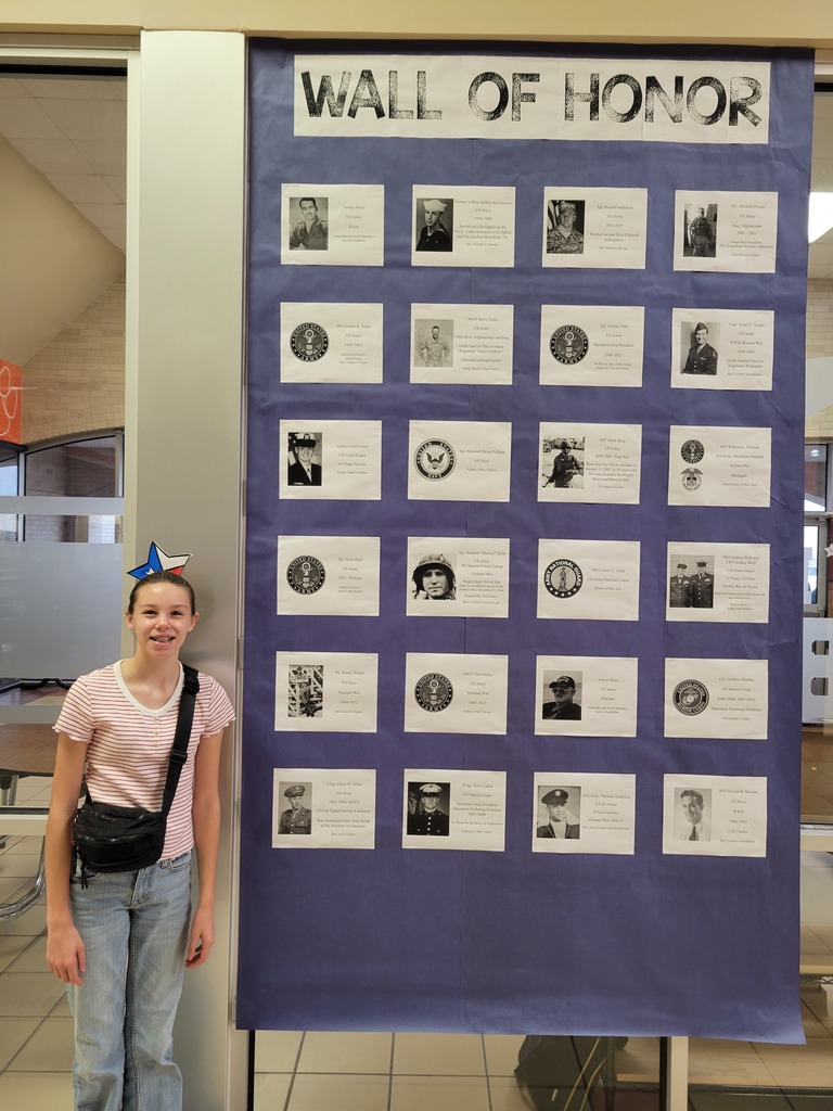 A student stands in front of StuCo's wall of honor for veteran's day